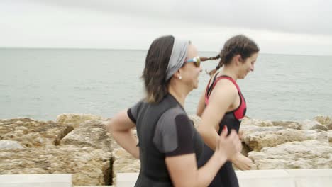 focused female triathletes running along seaside promenade