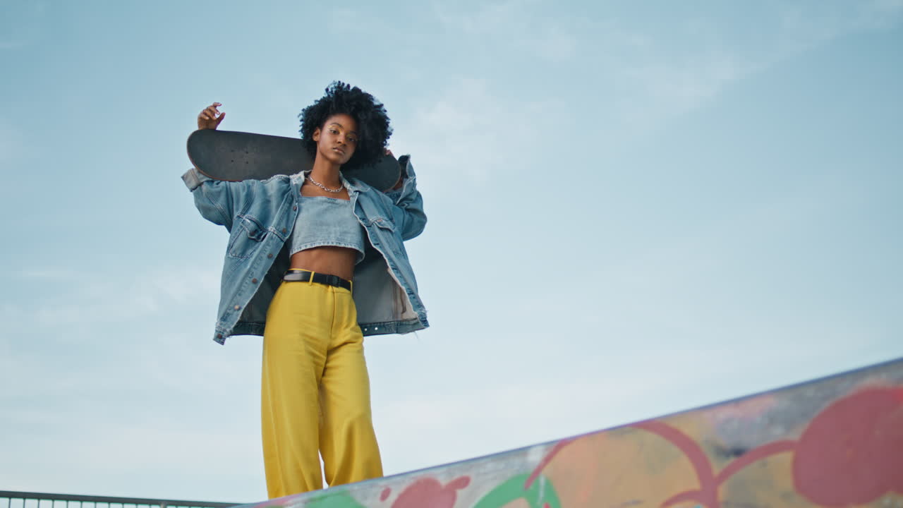 patinador caminando por la calle con una tabla larga en los hombros. chica genial