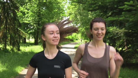 two pretty sportswomen running outdoors in the park 1