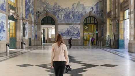 4k gimbal tracking shot of woman gazing up at art within são bento station