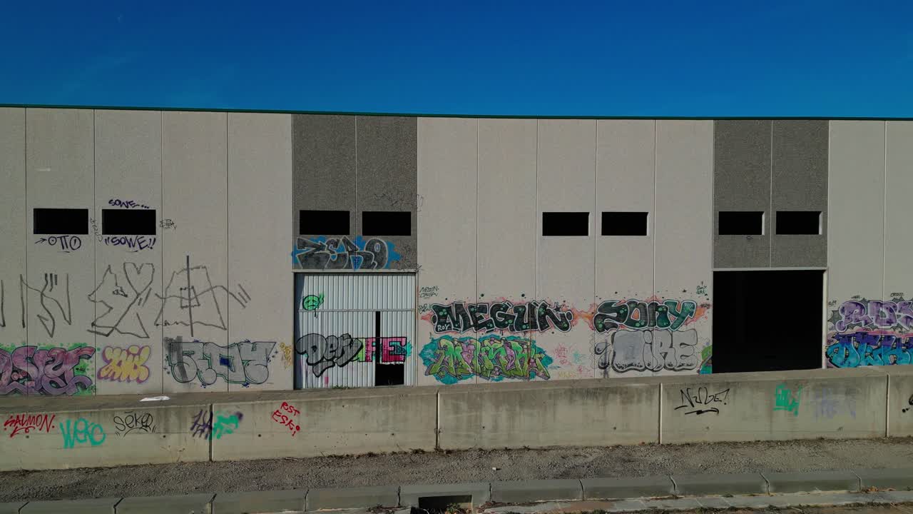 Muro di magazzino coperto di graffiti sotto un cielo blu, Abrera, Barcellona, Spagna, arte urbana, vista aerea