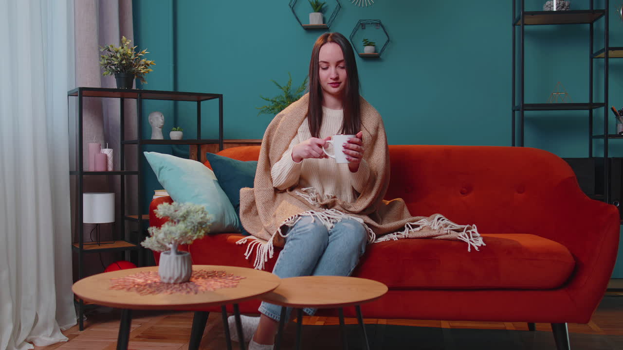 따뜻한 색 스웨터를 입은 미소 짓는 젊은 성인 여성의 초상화 가정에서 휴식을 취하는 뜨거운 음료 컵