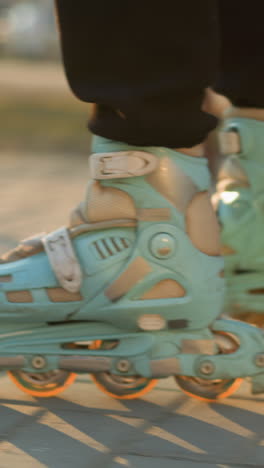 un primer plano capturando los pies de una persona usando patines, deslizándose suavemente a lo largo de un camino pavimentado en un parque durante la puesta de sol