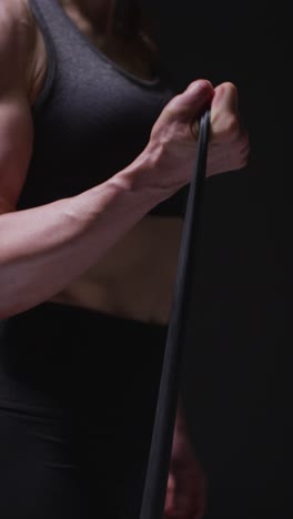 video vertical de primer plano de una mujer madura con ropa de gimnasia haciendo ejercicio con banda de resistencia 1