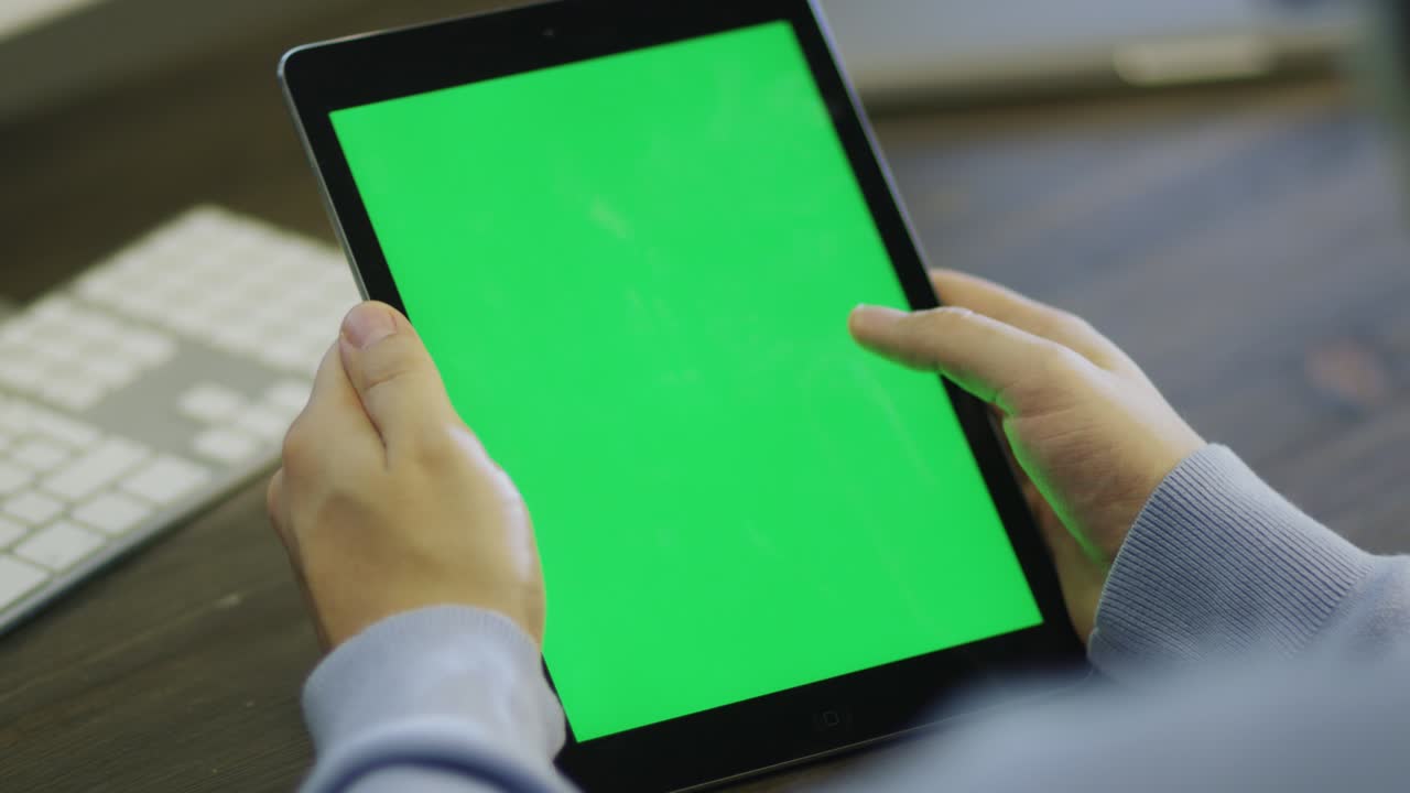 작업 중 초상화 모드에서 녹색 화면을 가진 디지털 태블릿을 사용하는 디자이너.