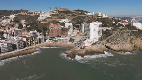 flyover of colorful rooftops near beach with sea glimmering in distance
