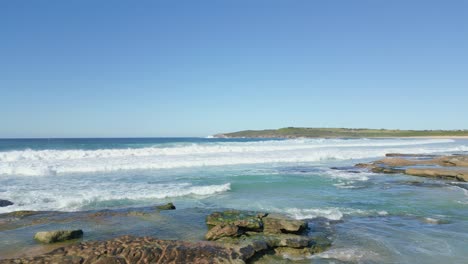 Aerial-drone-flying-low-heading-to-the-ocean-at-Maroubra-Beach,-Sydney---Australia