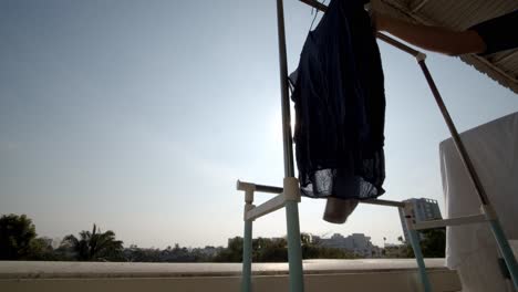 a person hangs laundry to dry on his apartment balcony on a sunny day - isolated low angle view