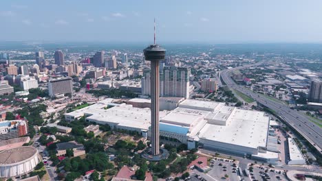 The Hemisfair Tower, also known as the Tower of Americas, sits in the heart of downtown San Antonio Texas surrounded by tall buildings, crowded highways and bustling city life