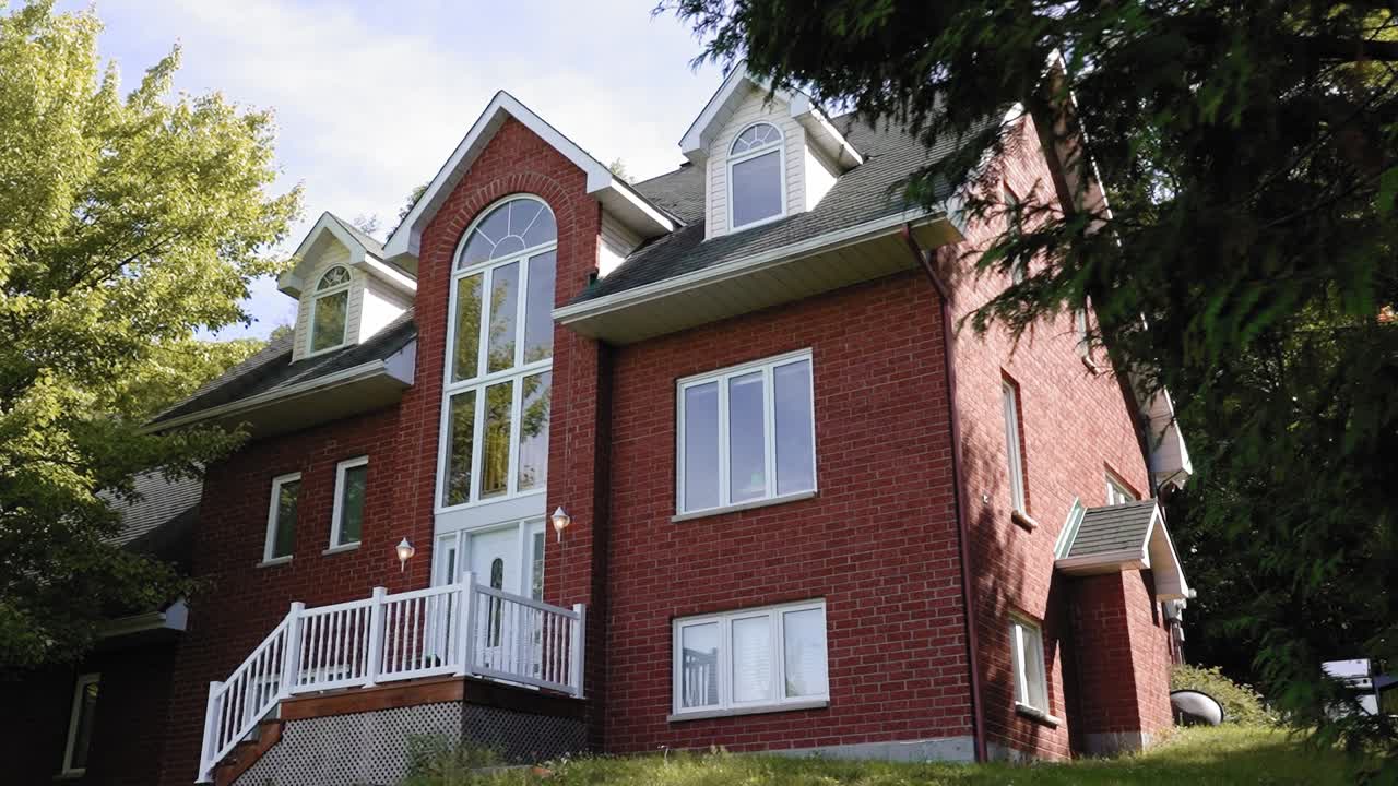 hermosa revelación de una hermosa casa de ladrillo rojo detrás de un árbol espeso y espeso en medio del bosque en quebec, canadá