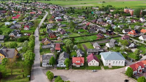 Establishing-drone-shot-of-small-village-in-Lithuania-surrounded-by-green-fields,-Sveksna