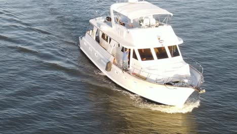 man come out of the door of a white luxury yacht cruising at sunset