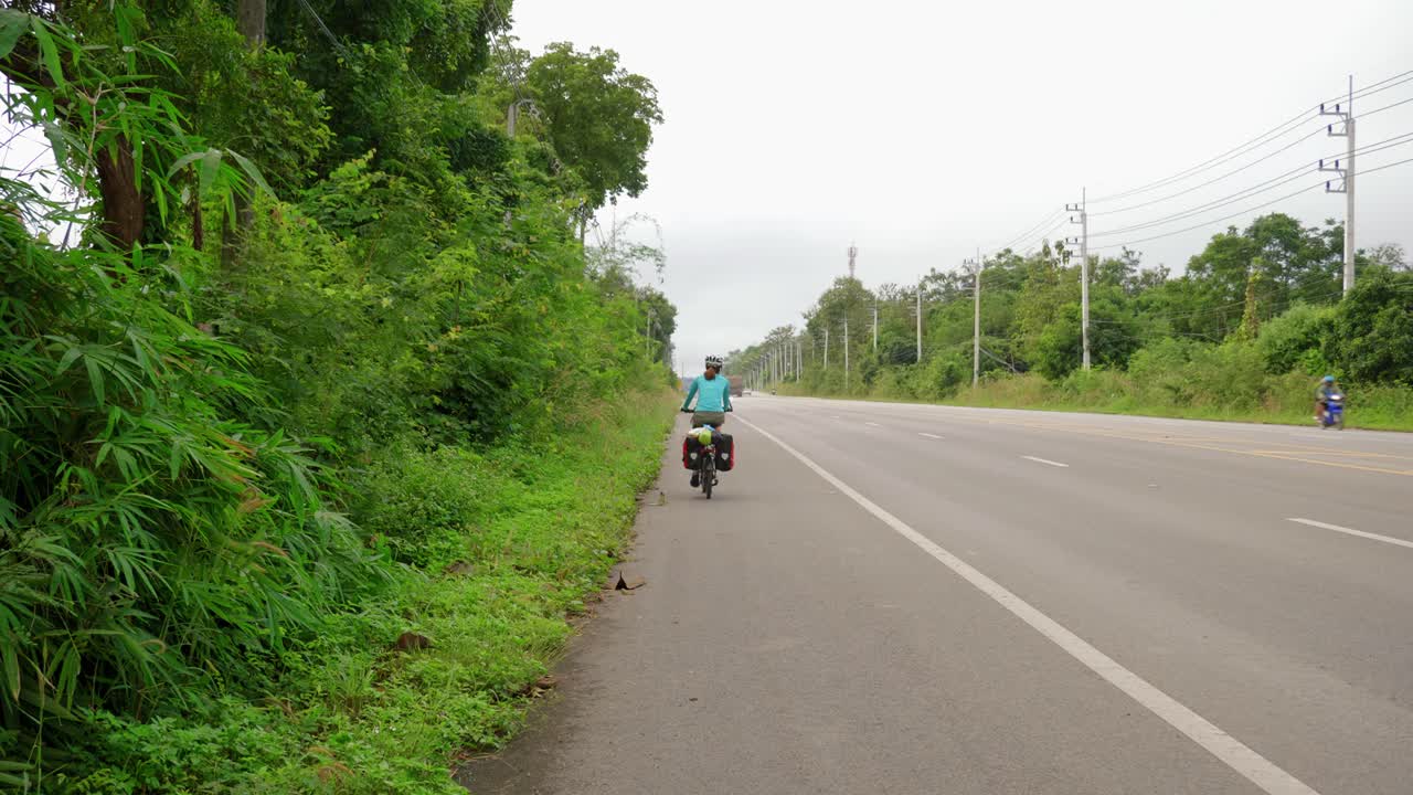 동남아 도로 갓길에서 자전거를 타는 스포츠우먼의 뒷모습