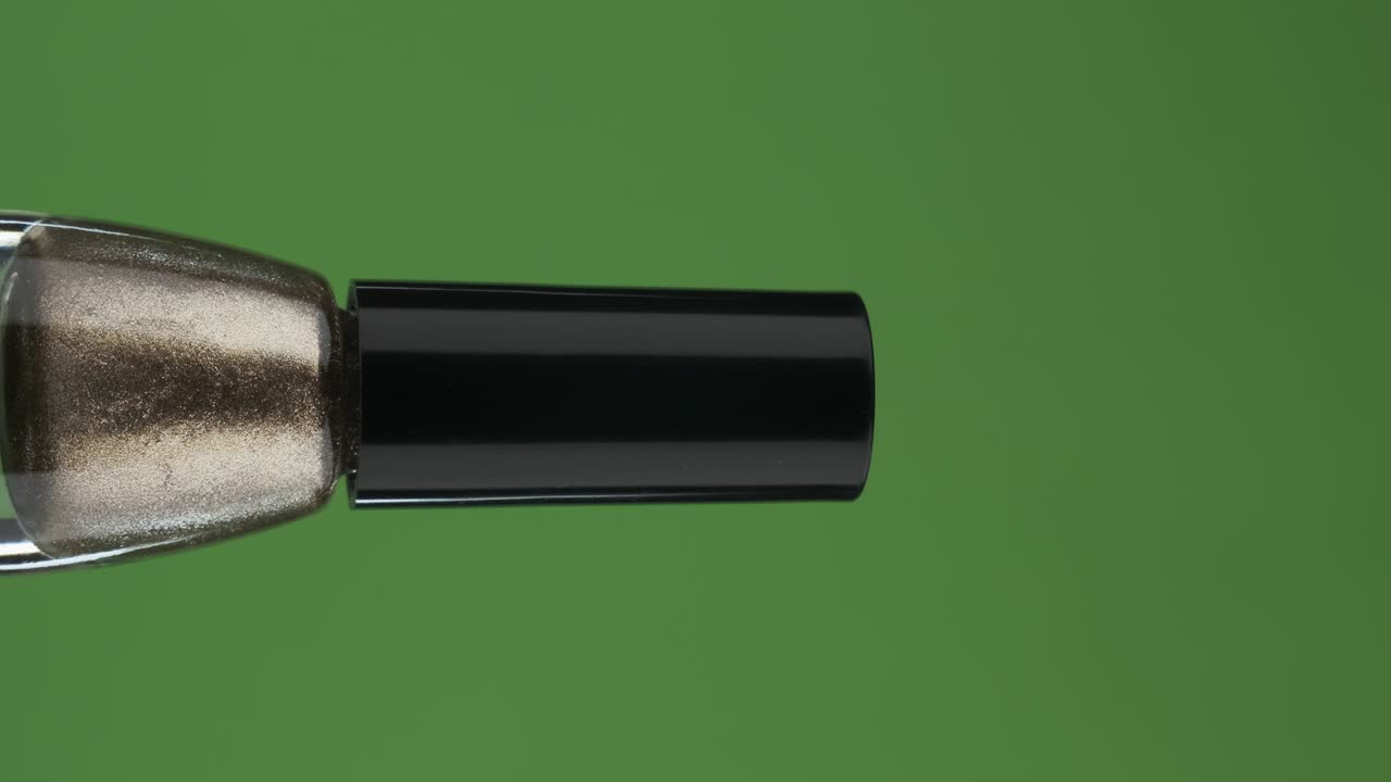 rotación horizontal de una botella de vidrio con esmalte de uñas, en una pantalla verde. primer plano.