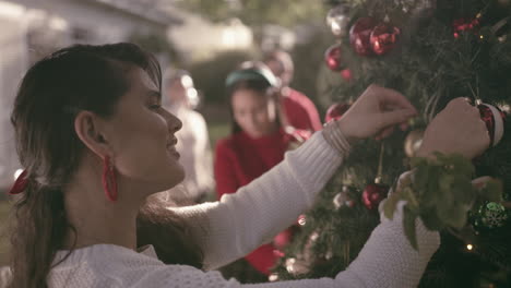 friends decorating christmas tree in backyard