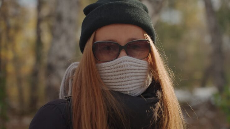 Donna che cammina attraverso la foresta. Una donna attenta si muove nella natura. Donna velata con zaino che si aggira in una fitta foresta. Donna con occhiali da sole e sciarpa che fa passi svelti in un'area boschiva.