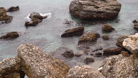 static view over beach rocks with calm waves rolling in