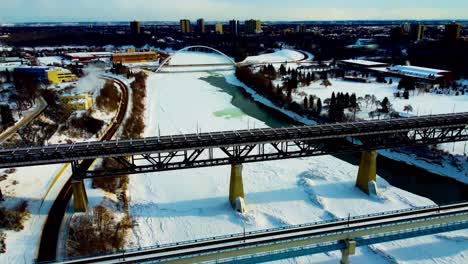 winter afternoon aerial flyover drop dolly roll birds eye view over bridges of public transit high level and white modern walter dale north saskatchewan river inbetween victoria kinsmen park blu3-4