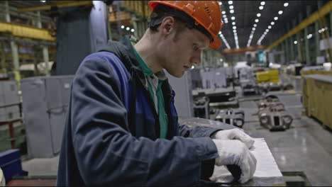 trabajador de fábrica inspeccionando una parte metálica