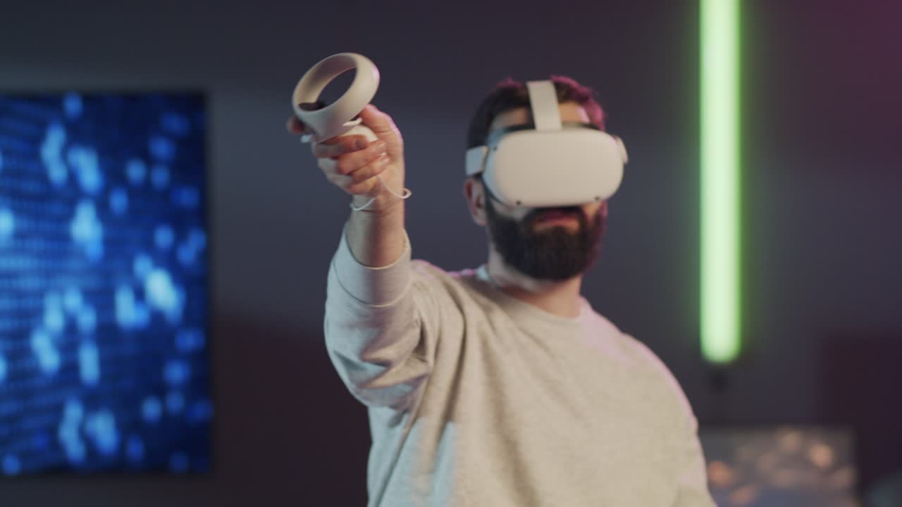 A bearded man wearing a VR headset uses controllers to paint, design, or sculpt in an immersive virtual world. The futuristic setting with neon lights emphasises creative technology and the metaverse.