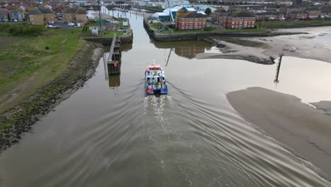 Boat-nearing-narrow-marina-entrance-on-calm-water-at-dusk-on-the-River-Wyre-Estuary-Fleetwood-Lancashire-UK