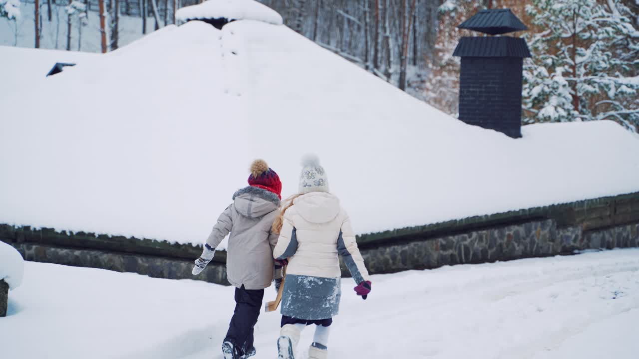 A little boy and girl looked at the image on the envelope not far from the building and are running an ahead along the path near the winter forest.