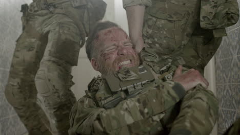 homens em uniforme de camuflagem carregando amigo ferido no braço