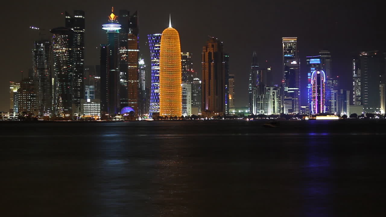 Dohas skyline om natten Time-lapse, Qatar. Vidvinkelbilde, moderne skyskrapere og tårn med havet om natten. Høye bygninger i sentrum, Midtøsten