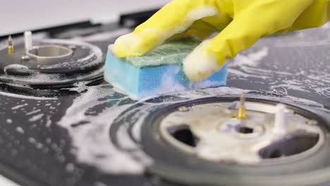 cleaning kitchen gas stove. womans hand cleaning gas stove with sponge
