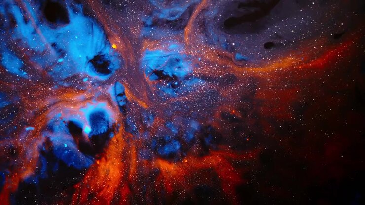 Blue and orange Nuovi Inchiostri pigments billow across black liquid, forming a space-style swirl filled with tiny bright specks.