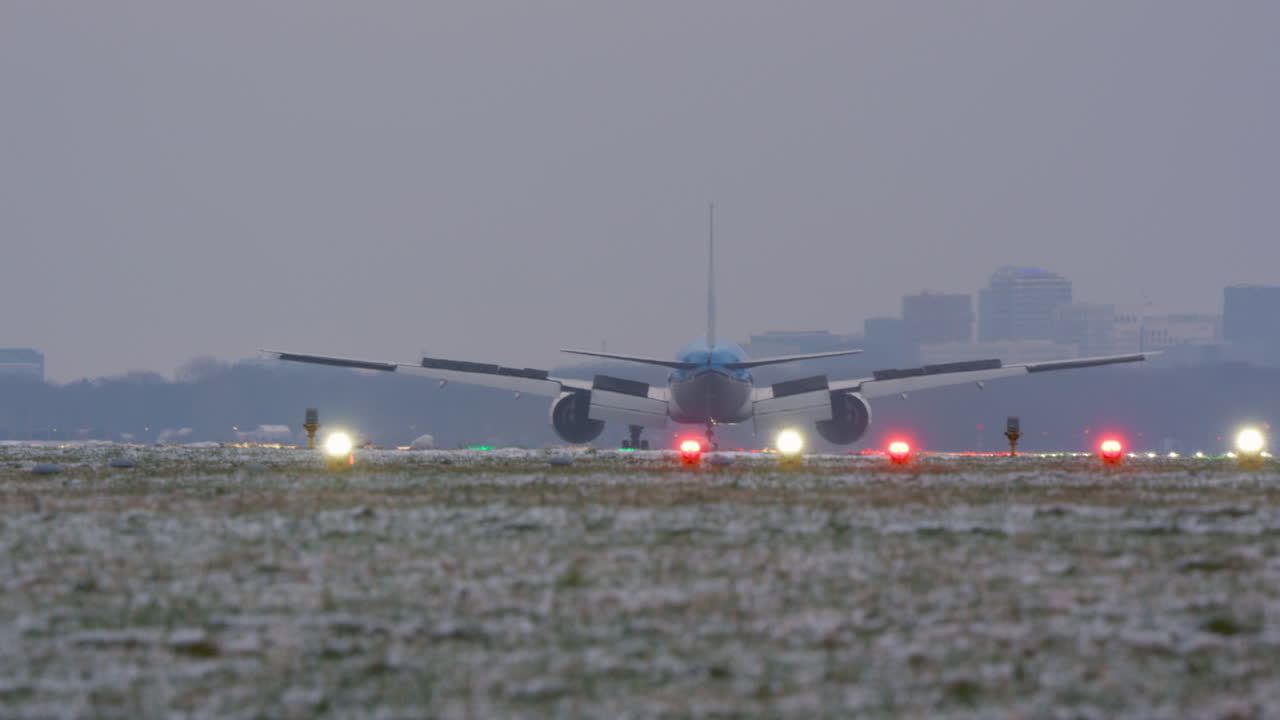 Atterraggio e rullaggio di un grande aereo passeggeri su una pista innevata al tramonto