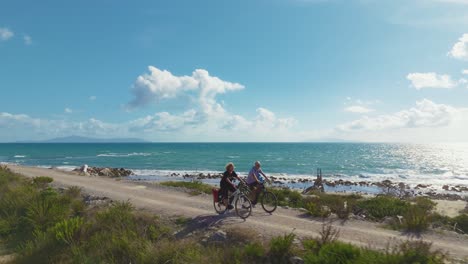 married senior couple riding electric pedelec bikes, active and sporty tour in italy by the sea.
