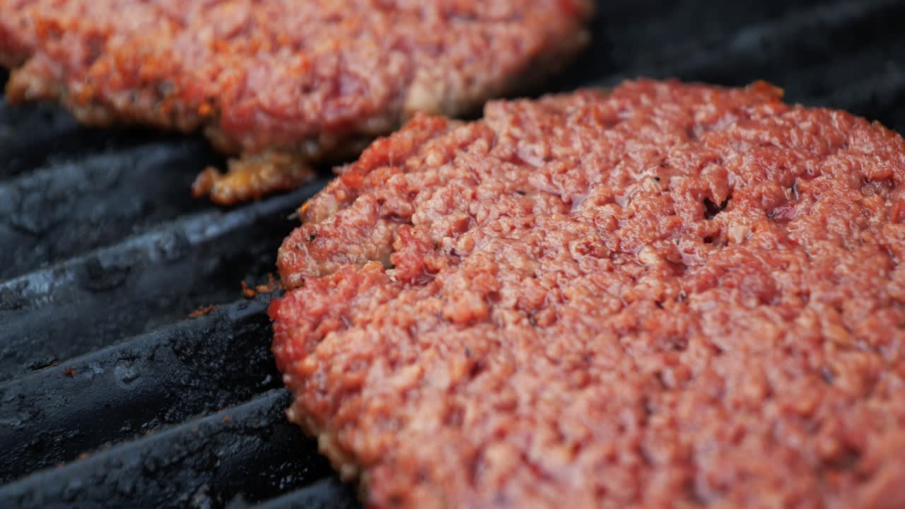 hamburguesas imposibles basadas en una planta de barbacoa en una parrilla eléctrica toma de primer plano que se desplaza hacia abajo y hacia arriba para revelar otra hamburguesa que se vuelve marrón mientras cocinan - en el cine 4k