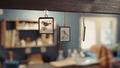 glass decorations with painted birds hanging in a kitchen, symbolizing artistry and warmth, with dominant neutral and wooden tones in a cozy home setting.
