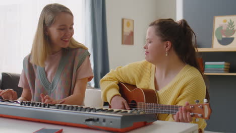 girl with down syndrome playing guitar as music teacher using synth