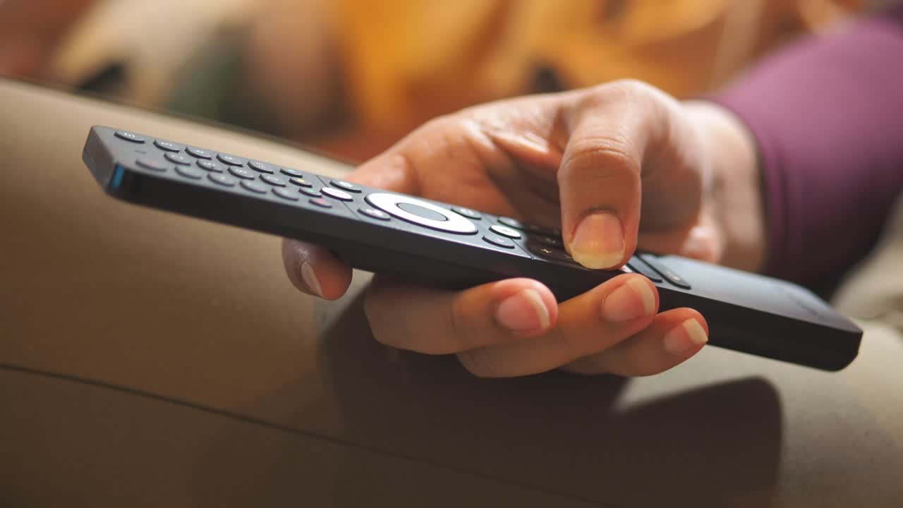 Primo piano di una mano che preme un pulsante sul telecomando