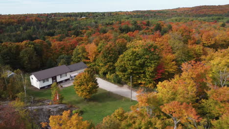 Countryside-House-surrounded-by-Beautiful-Autumnal-foliage,-seasonal-Landscape,-Aerial-Orbiting