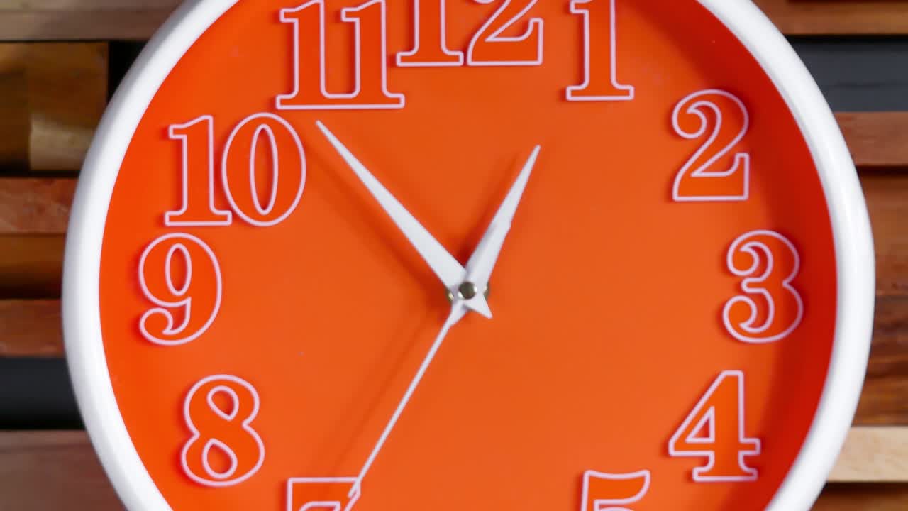 Zoom out close up time-lapse of modern wall clock approaching seven o' clock themes of deadline appointment late departure on a wood background.