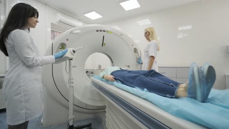 female patient is undergoing ct or mri scan under supervision of two qualified radiologists in modern medical clinic. patient lying on a ct or mri scan table, leaves the machine