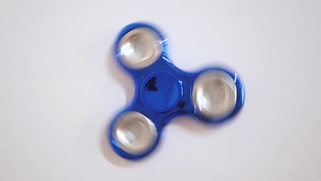 juguete para relajarse conocido con spinner en color azul con fondo blanco.
