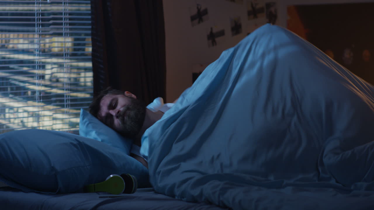 Man in bedroom, night time, listening to music and sleeping