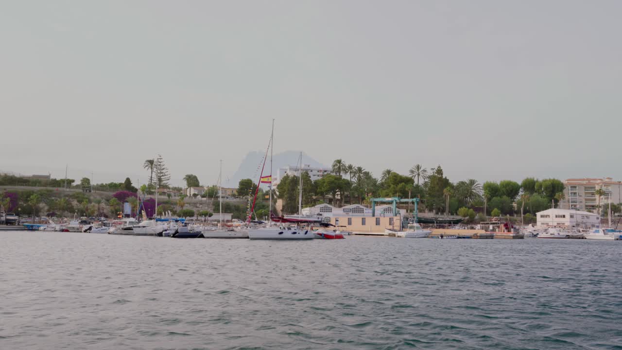 vista desde el mar del puerto de villajoyosa con la montaña de puig campana en el fondo y barcos y veleros