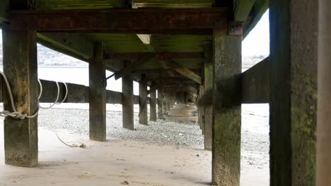 under timber coastal wooden fishing jetty tourism beach at low tide left dolly shot