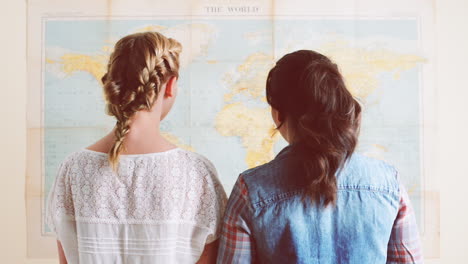 tourist girls looking at world map planning travel adventure