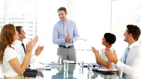 Businessman-receiving-praise-from-his-employees-at-meeting