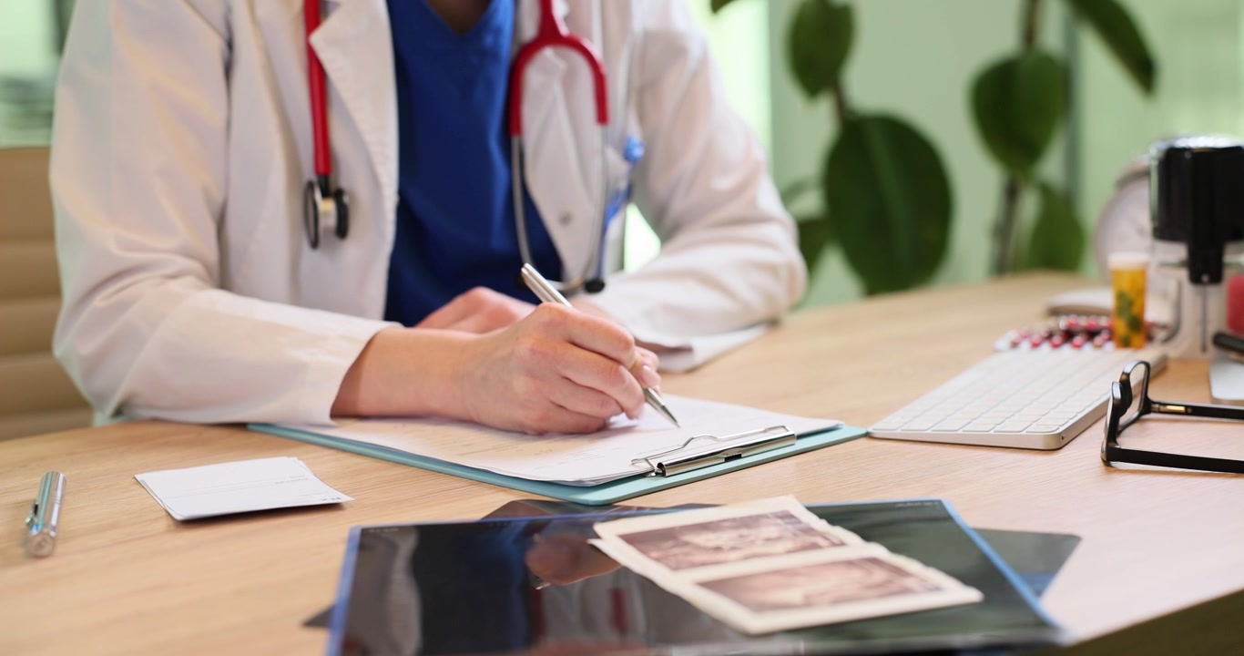 Médica con bata anota registros médicos en un portapapeles.
