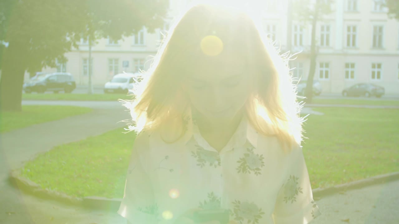 해가 뜨는 시내 공원에서 스마트폰을 사용하는 젊은 여성.