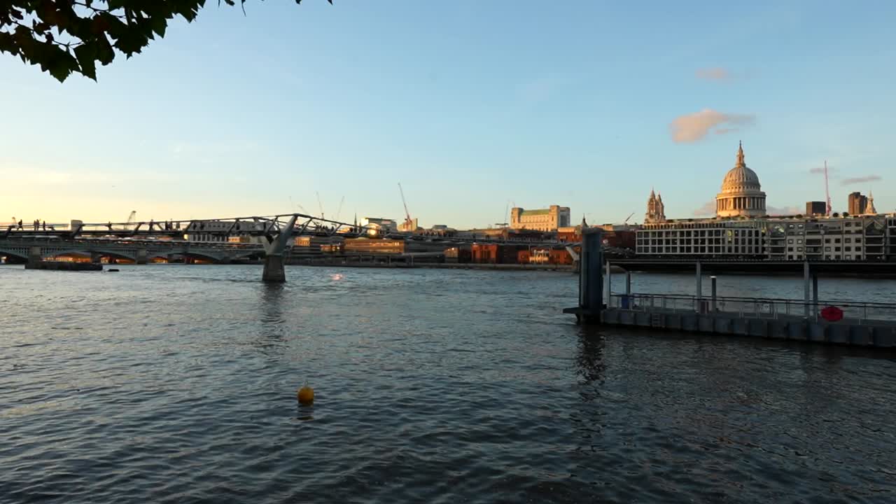 Millennium Bridge and St Paul's Cathedral at sunset with the Thames River flowing in between
