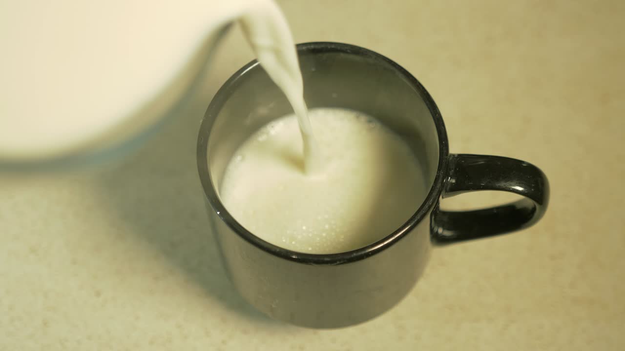 Ripresa dall'alto di latte caldo fumante versato in una tazza nera