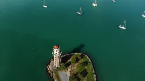 Luftbildansicht-Von-Luxusyachten,-Die-Ankern,-Leuchtturm,-Türkisfarbenes-Wasser